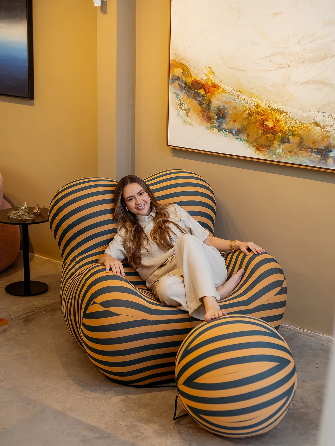 Fhiama Fonseca sentada em poltrona autoral da Casa in Gold